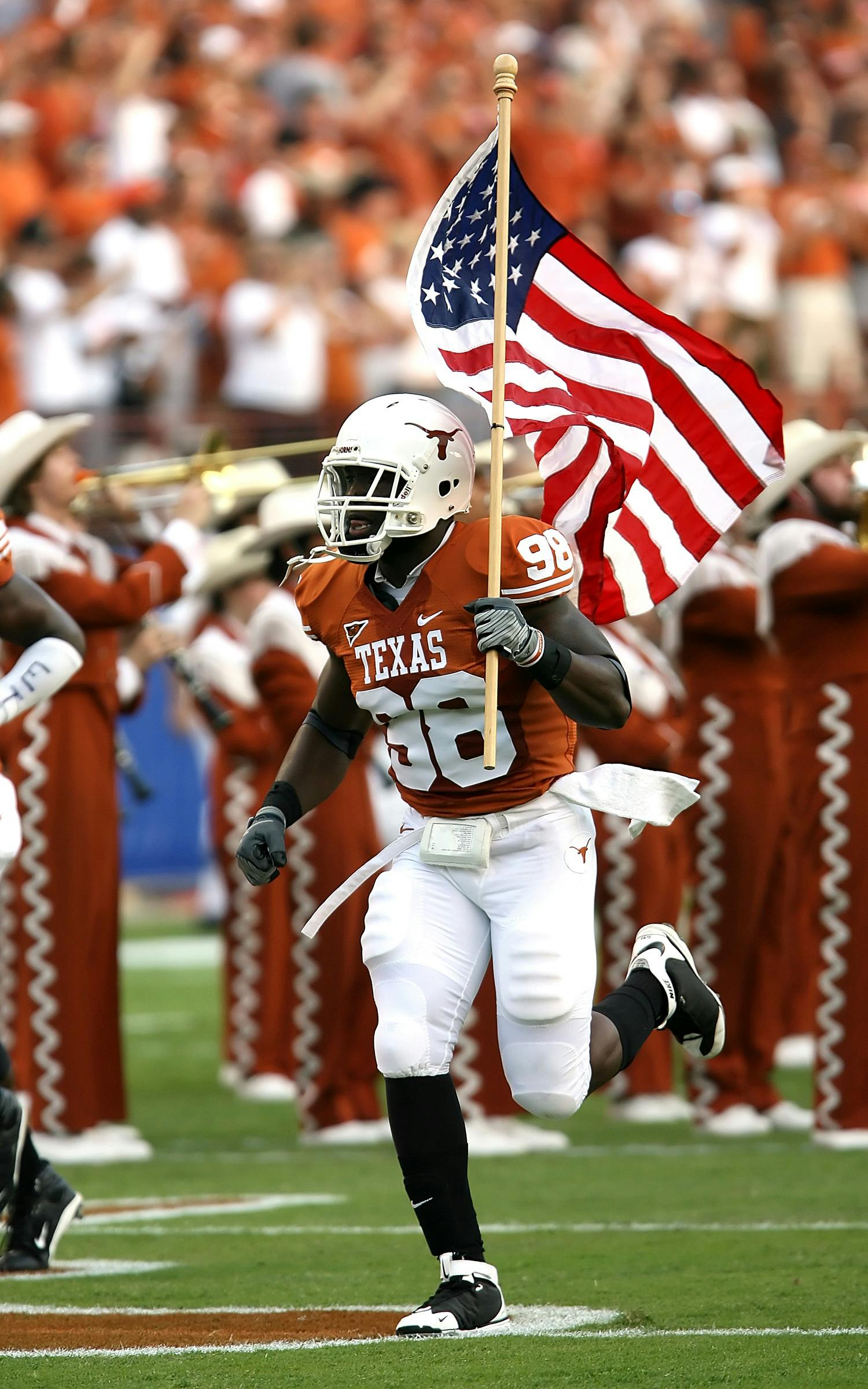 A football player from the Texas Longhorns running across a field with a flag. The player has strong athlete branding.